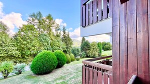 A two-story building with a wooden balcony, surrounded by well-maintained lawns and trees. - Charming apartment facing Mont Blanc (combloux)