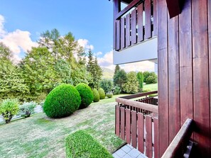 Un bâtiment à deux étages doté d’un balcon en bois, entouré de pelouses et d’arbres bien entretenus.