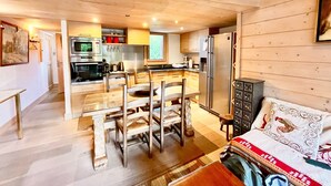 A modern kitchen with stainless steel appliances, a dining area with wooden furniture, and a cozy living space with a sofa and decorative pillows. - Charming apartment facing Mont Blanc (combloux)