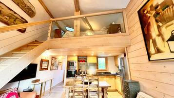 Une cabane en bois à plusieurs niveaux, comprenant un coin repas, une cuisine et un escalier.