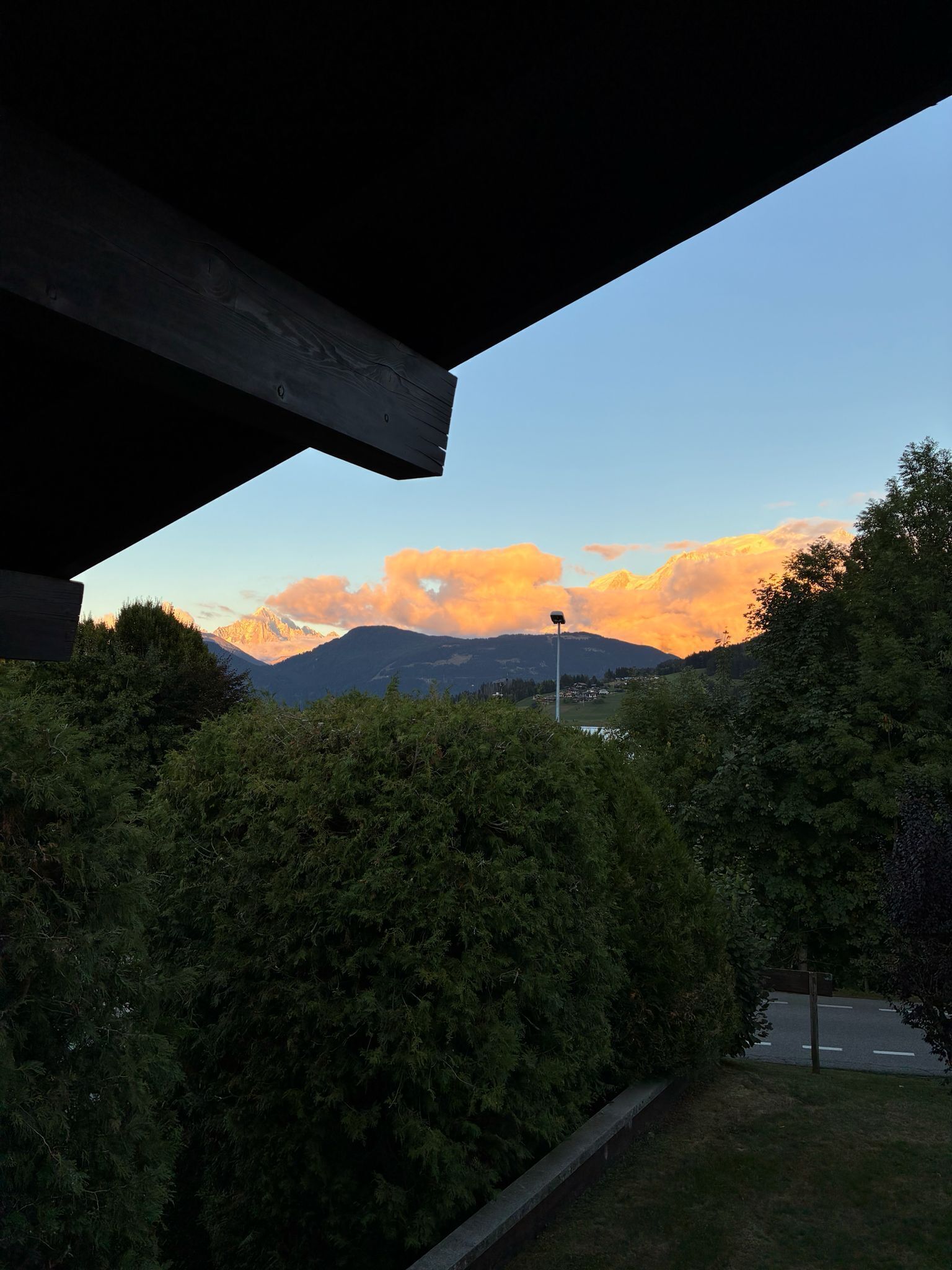 Une vue à travers la fenêtre d’un bâtiment, donnant sur une chaîne de montagnes sous un ciel dégagé.