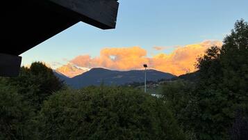 Une vue à travers la fenêtre d’un bâtiment, donnant sur une chaîne de montagnes sous un ciel dégagé.