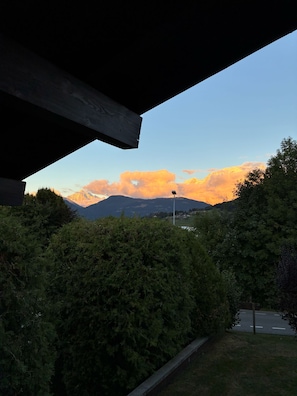 A view through a building's window overlooking a mountain range with a clear sky. - Charming apartment facing Mont Blanc (combloux)