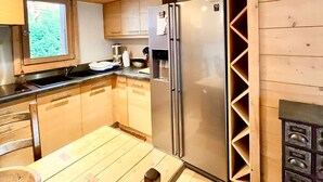 A wooden-paneled kitchen with a refrigerator, sink, and wooden table. - Charming apartment facing Mont Blanc (combloux)