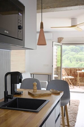 A modern kitchen with a built-in microwave, a sink, and a pendant light. - La Escondida Rural (San Martín de Valdeiglesias)