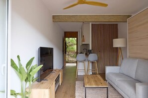Ein modernes Wohnzimmer mit Sofa, Couchtisch, Fernseher und Pflanze.