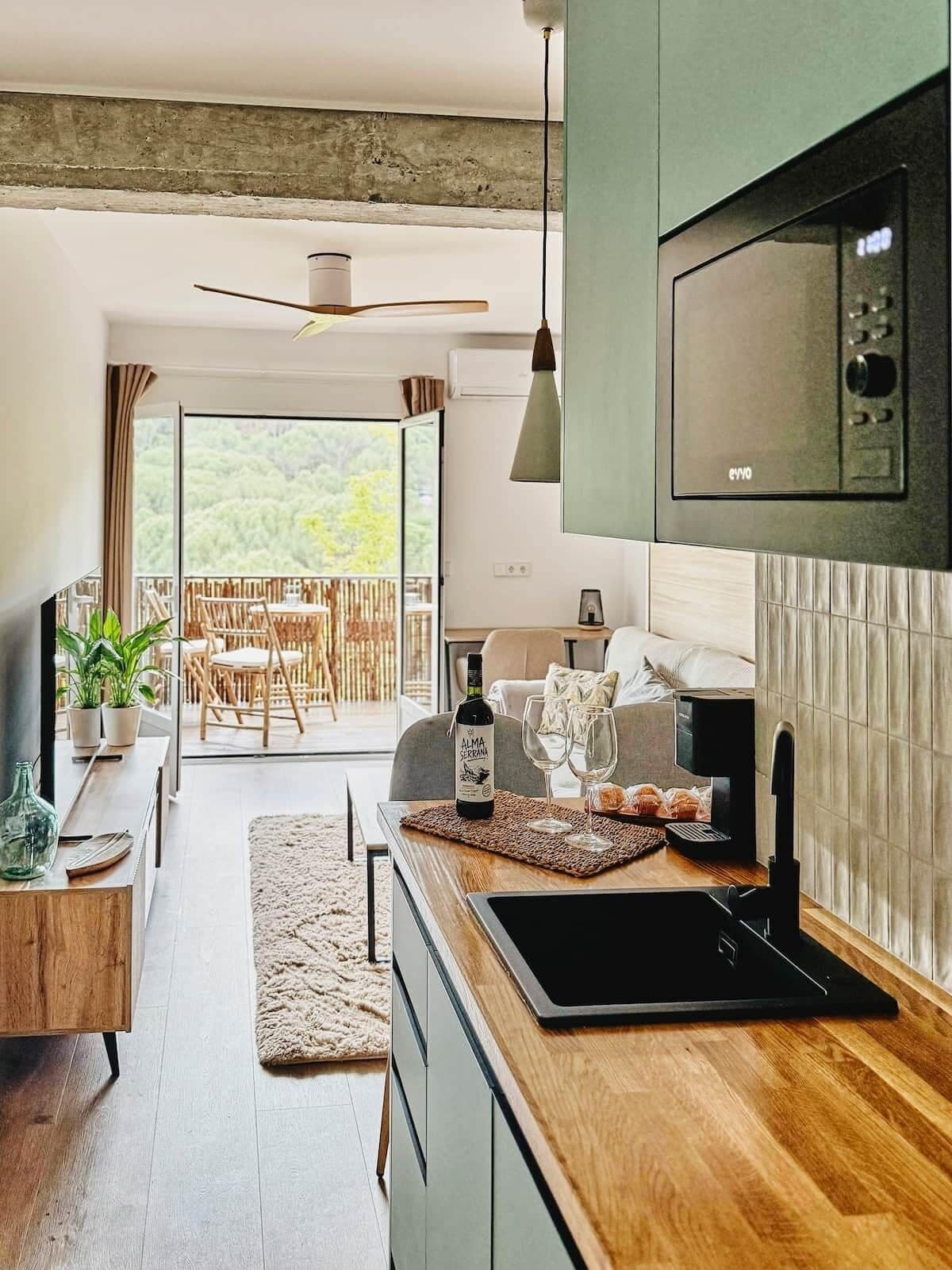 A modern kitchen with a built-in microwave, a dining area with a table and chairs, and a view of the outdoors.