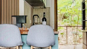 A kitchen with two bar stools, a hanging light fixture, and a bottle of wine on the counter. - La Escondida Apartment at the San Juan B Reservoir (San Martín de Valdeiglesias)