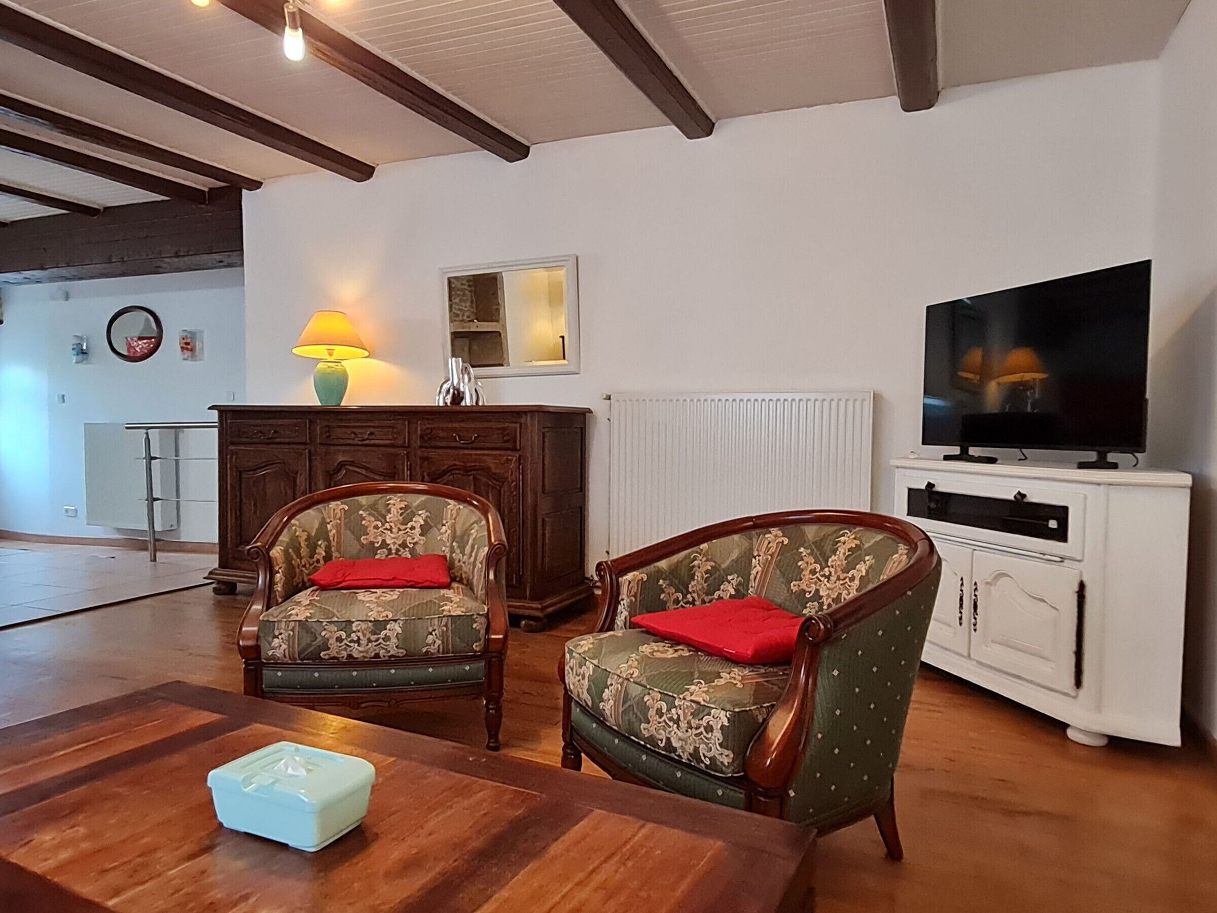 A living room with two upholstered chairs, a wooden coffee table, a television, and a cabinet.
