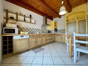 A kitchen with wooden cabinets, a microwave, a sink, and a dining area with a table and chairs.