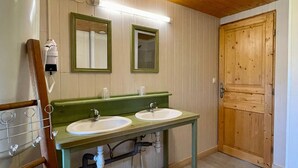A bathroom with two sinks, wooden walls, a wooden door, and a towel rack.