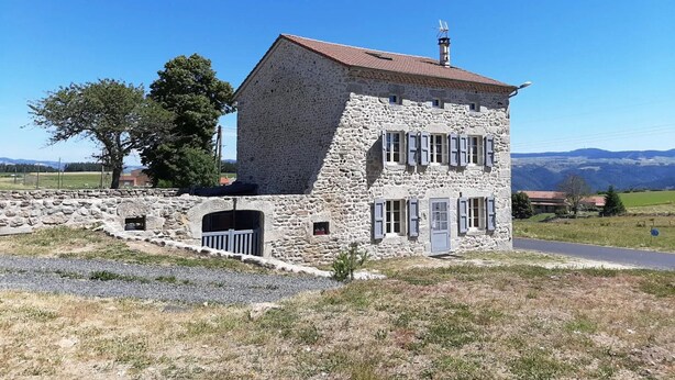 A stone building with a red roof, a small entrance, and a staircase leading up to it.