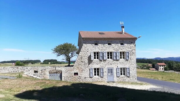 A stone building with a red-tiled roof, multiple windows, and a chimney. - Rustic family retreat in the Allier Gorges, nature and hiking nearby (Alleyras)