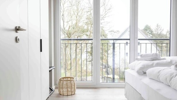 Quarto com cama, janela, varanda e porta.