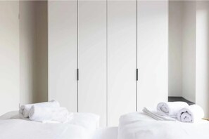 Ein Hotelzimmer mit einem Bett, zwei aufgerollten Handtüchern und einem Schrank mit Spiegel.