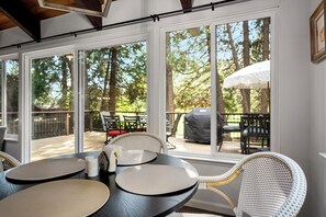 A sunroom with large windows, wicker furniture, and a grill outside. - Sequoia Meadow | Fairway Views & BLS Amenities (Arnold)