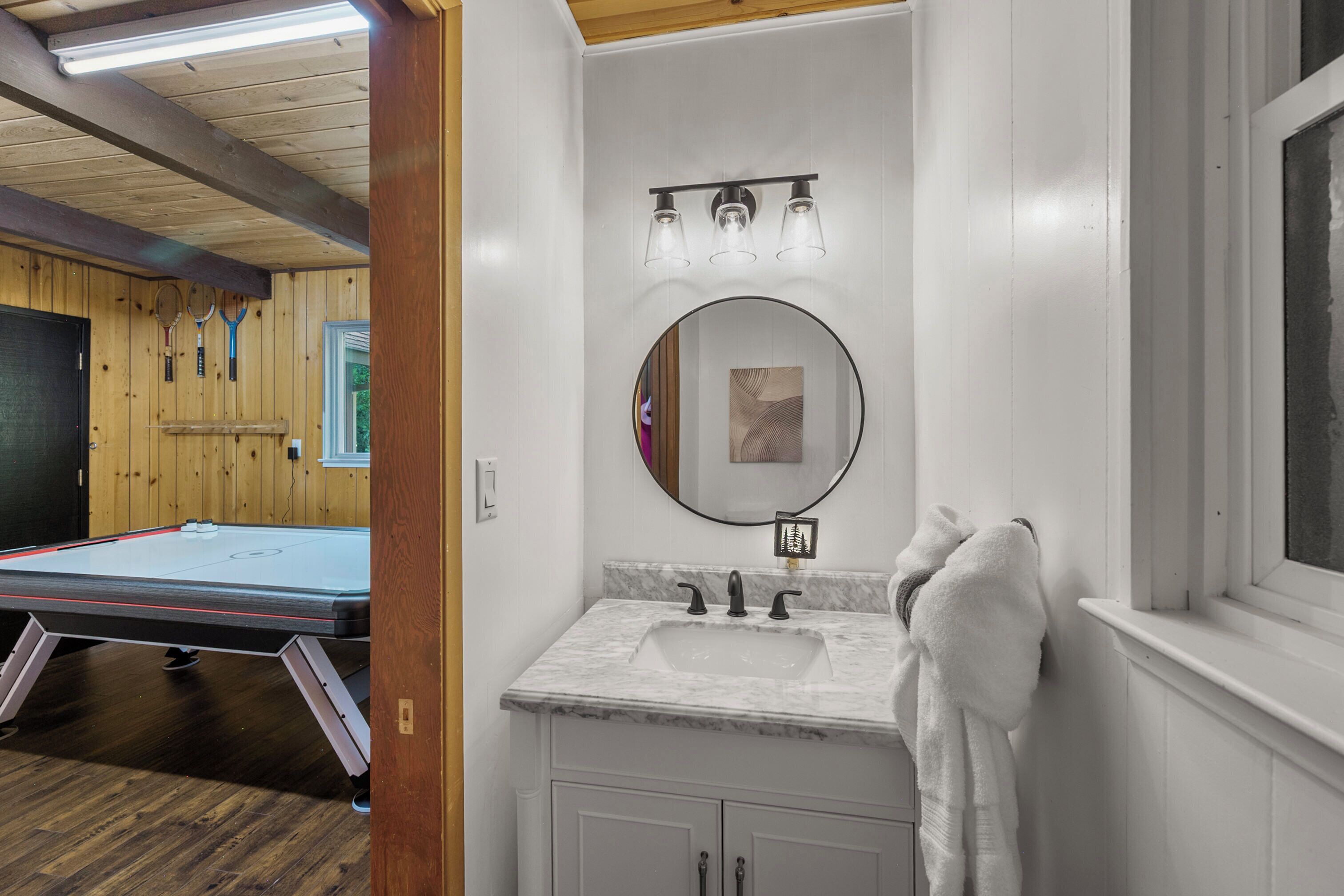 Een badkamer met een wastafel, spiegel en handdoekrek.