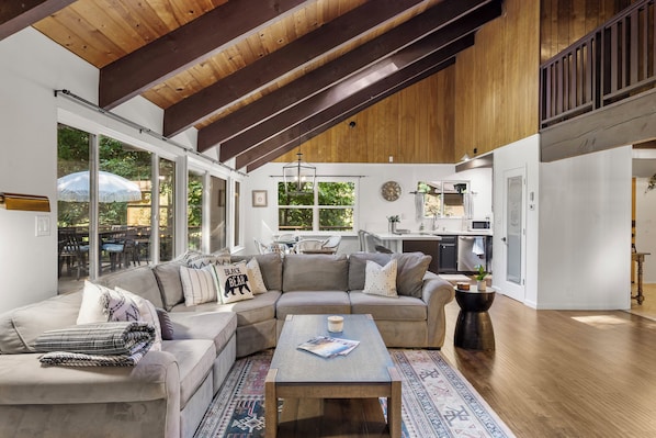 A spacious living area with a large sectional sofa, a coffee table, and a view of the outdoors through large windows.
