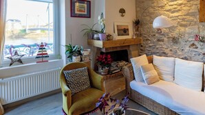 A cozy living room with a fireplace, a sofa, a chair, and a window with a view of a bridge.