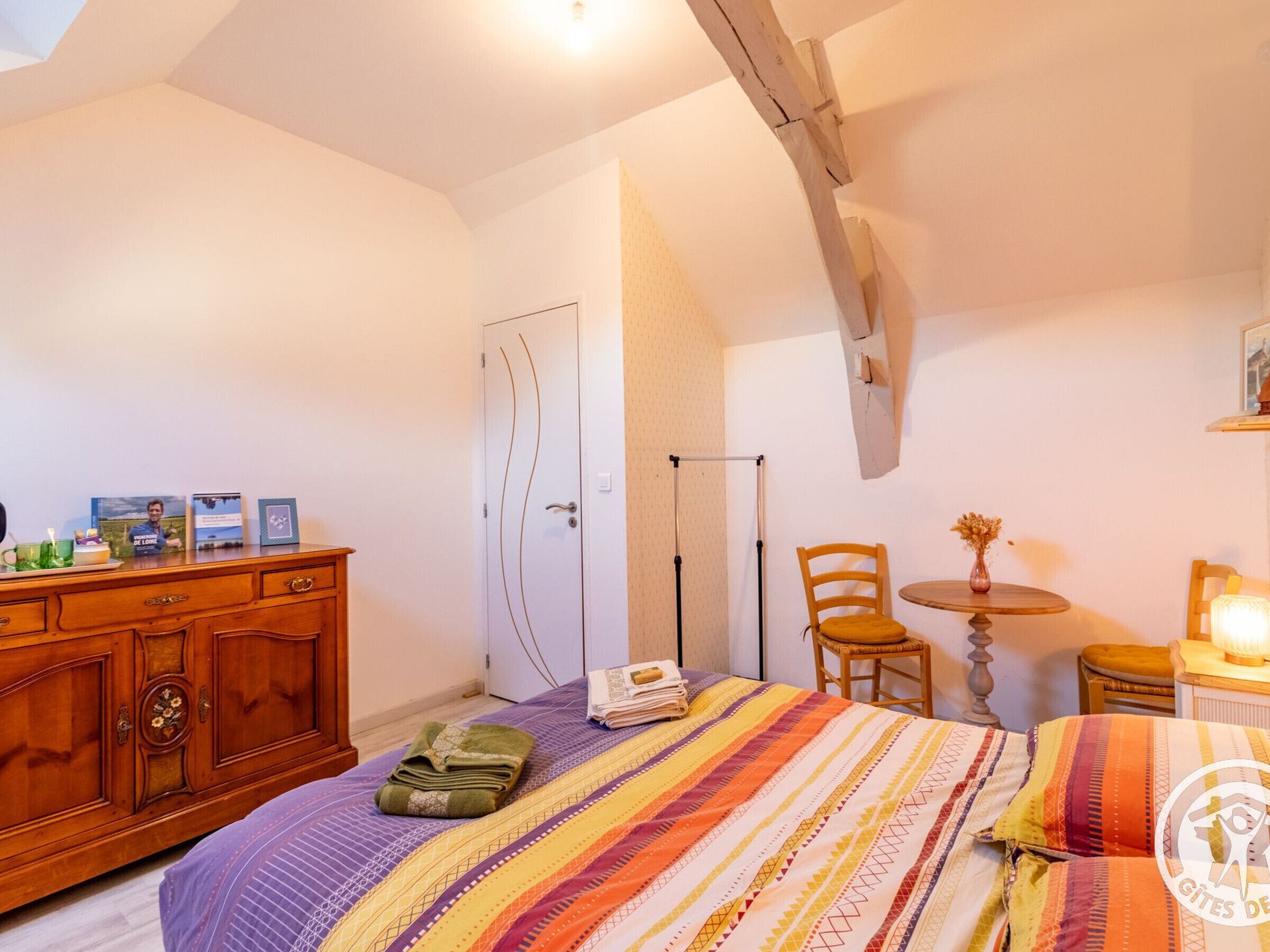 Ein Schlafzimmer mit einem Bett, einem Holzschrank und einem kleinen Tisch mit Stuhl.