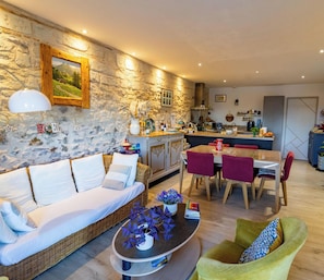 A cozy living room with a sofa, a dining table, and a kitchen area.