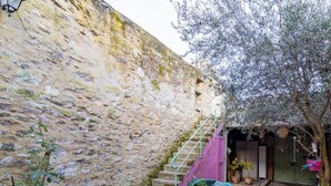 A stone wall, a staircase, and potted plants in a courtyard.
