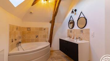 A bathroom with a freestanding bathtub, two wall-mounted mirrors, and a vanity with a black cabinet.
