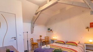 A cozy bedroom with a bed, a small table, chairs, and a desk.