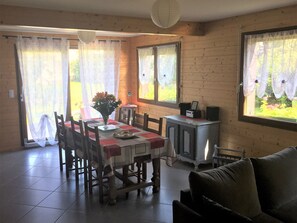 Ein Essbereich mit Tisch, Stühlen, einer Blumenvase, einem Schrank und einer Couch.