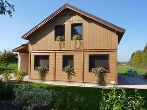 Ein zweistöckiges Holzhaus mit Blumenkästen an den Fenstern, einem gepflegten Rasen und blauem Himmel.