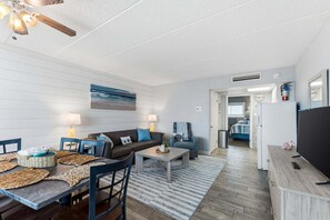 Ein modernes Wohnzimmer mit Essbereich, Deckenventilator, Kamin und Meerblick.