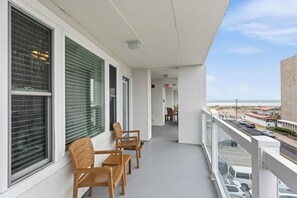 A balcony with a view of the beach, a door, and a chair. - Modern Beach Condo w/ Ocean Views, Pool & Prime Walkable Location (Wildwood Crest)