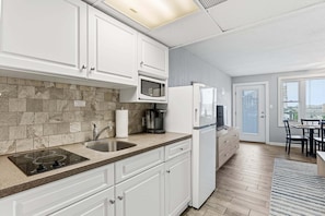 A modern kitchen with white cabinets, a built-in microwave, a refrigerator, and a sink. - Modern Beach Condo w/ Ocean Views, Pool & Prime Walkable Location (Wildwood Crest)