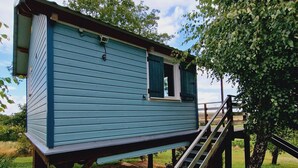 A blue wooden structure with a window and a staircase leading up to it.