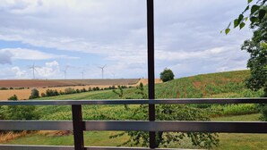 A view of wind turbines, green fields, and a wooden fence.