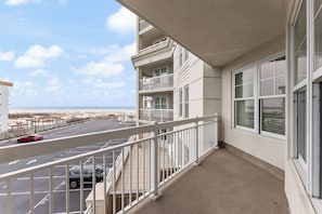 A balcony with a view of a parking lot and beach. - Residence 207 at The Grand (Wildwood)