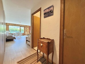 Ein Zimmer mit einer hölzernen Bank, einem kleinen Tisch und einer Tür zu einem anderen Raum.
