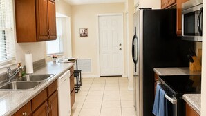 Una cocina con armarios de madera, un refrigerador, un microondas y una estufa.