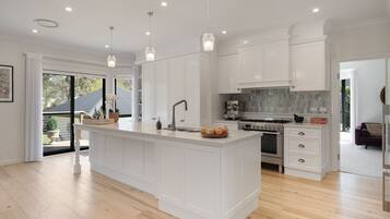 A modern kitchen with white cabinetry, a central island, a built-in oven, and a large window.