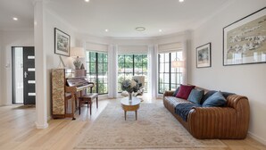 Uma sala de estar ampla, com um piano, um sofá e uma mesa de centro.