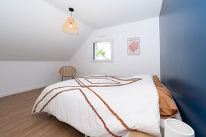 Ein Schlafzimmer mit einem Bett, einem Fenster, einer Wandleuchte und einem gerahmten Bild.
