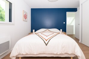 Une chambre à coucher comprenant un lit, une fenêtre, un radiateur fixé au mur et une porte donnant sur une autre pièce.