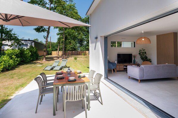 Un espace de vie à aire ouverte comprenant un téléviseur, un canapé et une table à manger avec des chaises.
