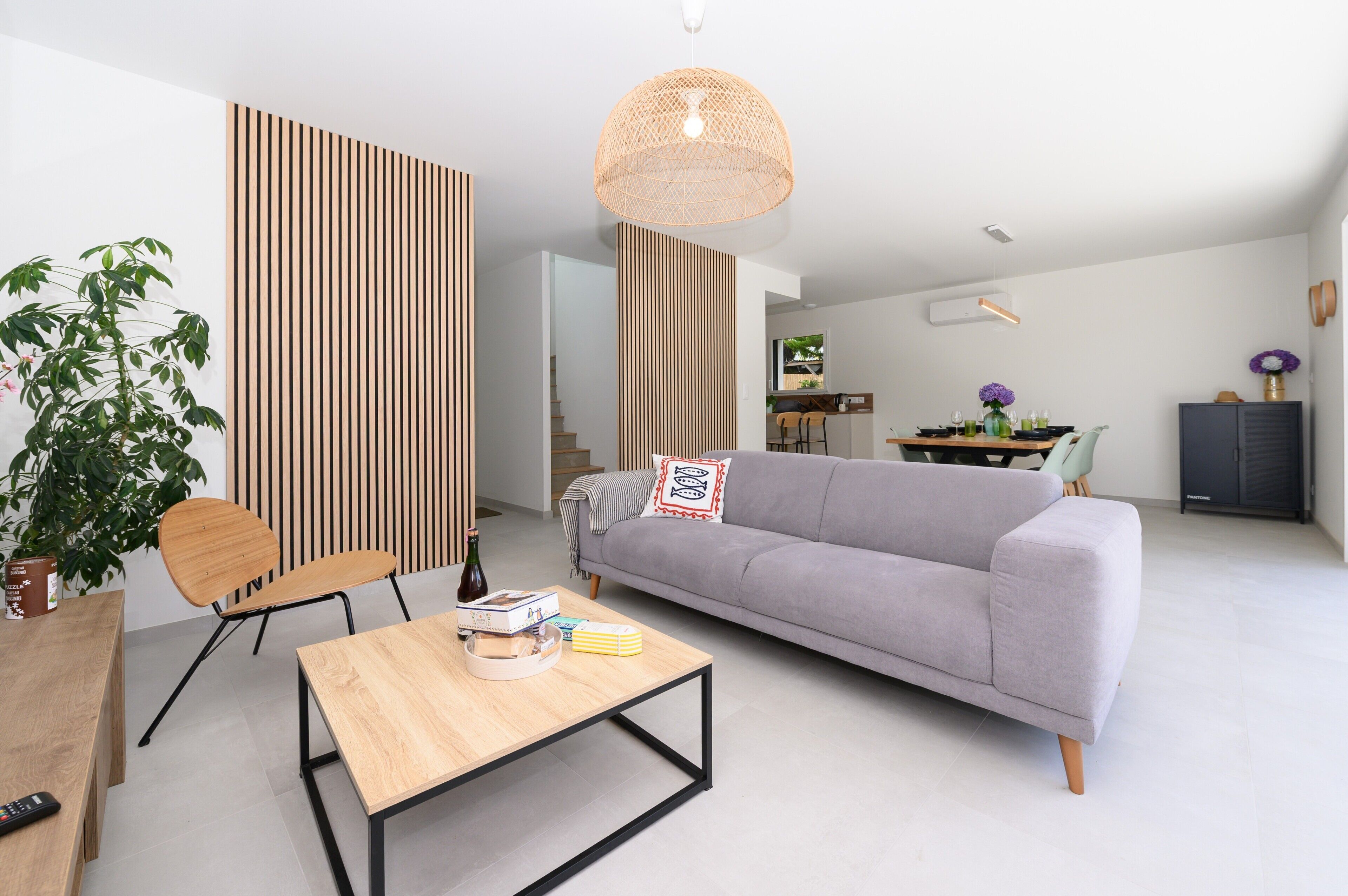 A modern living room with a grey sofa, wooden coffee table, and a hanging light fixture.