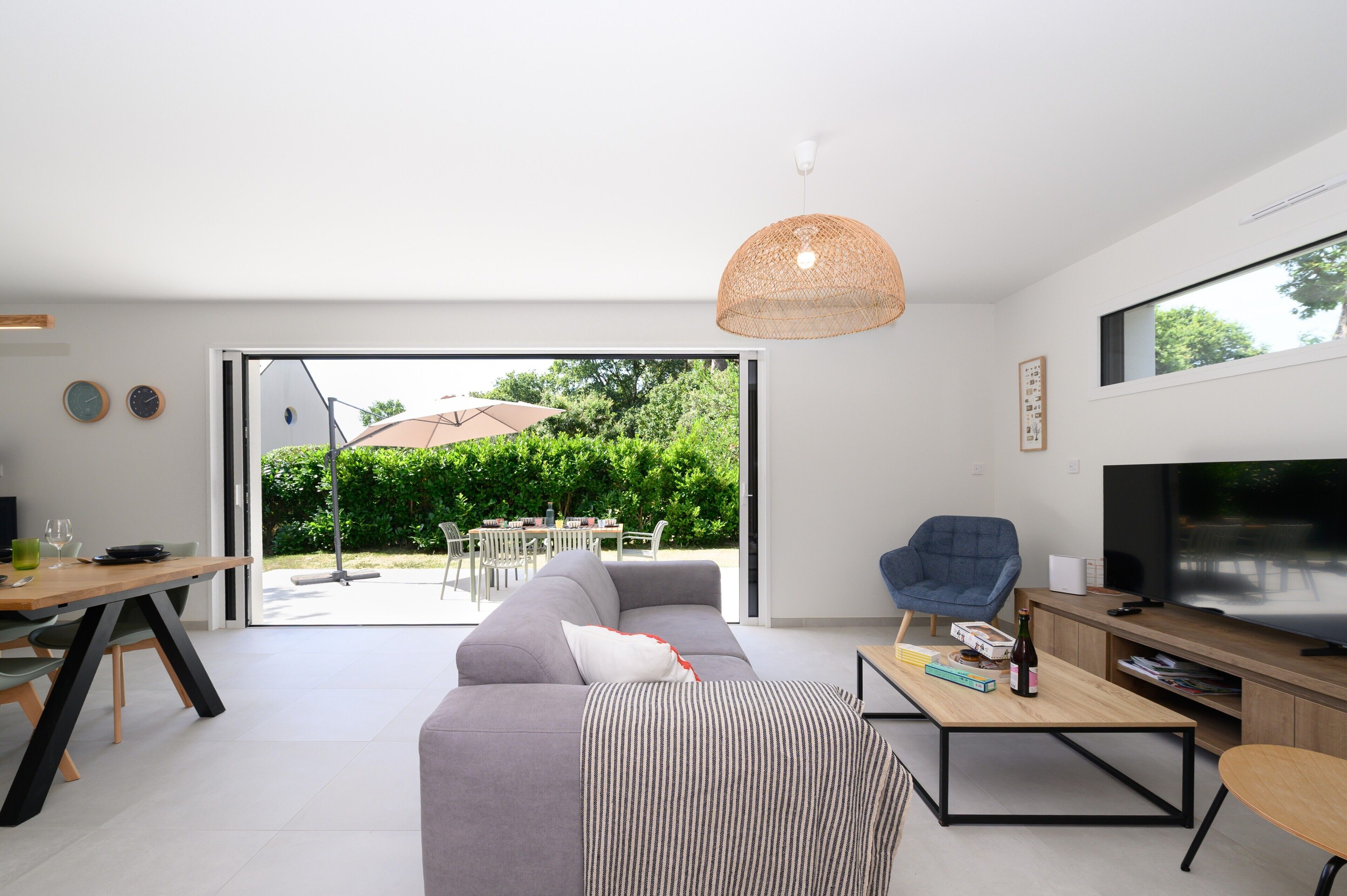 A modern living room with a sofa, coffee table, TV, and dining area with chairs and a table.