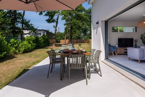 Une terrasse extérieure avec une table à manger, des chaises et un grand parasol.
