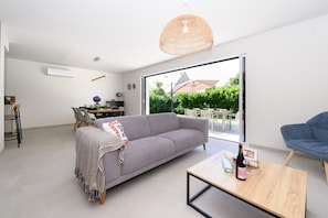 Ein modernes Wohnzimmer mit Sofa, Couchtisch und Essbereich.