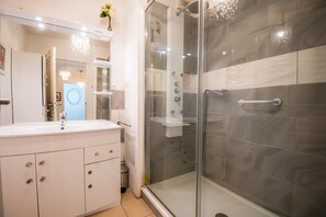 Un bagno moderno con doccia a vetro, un vanità bianca con specchio e lavabo.