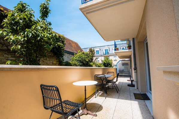 Un balcone con mobili da esterno, un muro in pietra e vista sugli edifici circostanti.