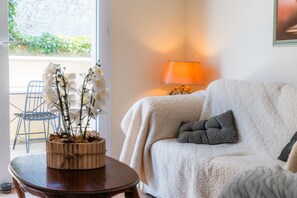 Una sala acogedora con un sofá, una lámpara y una orquídea en maceta.